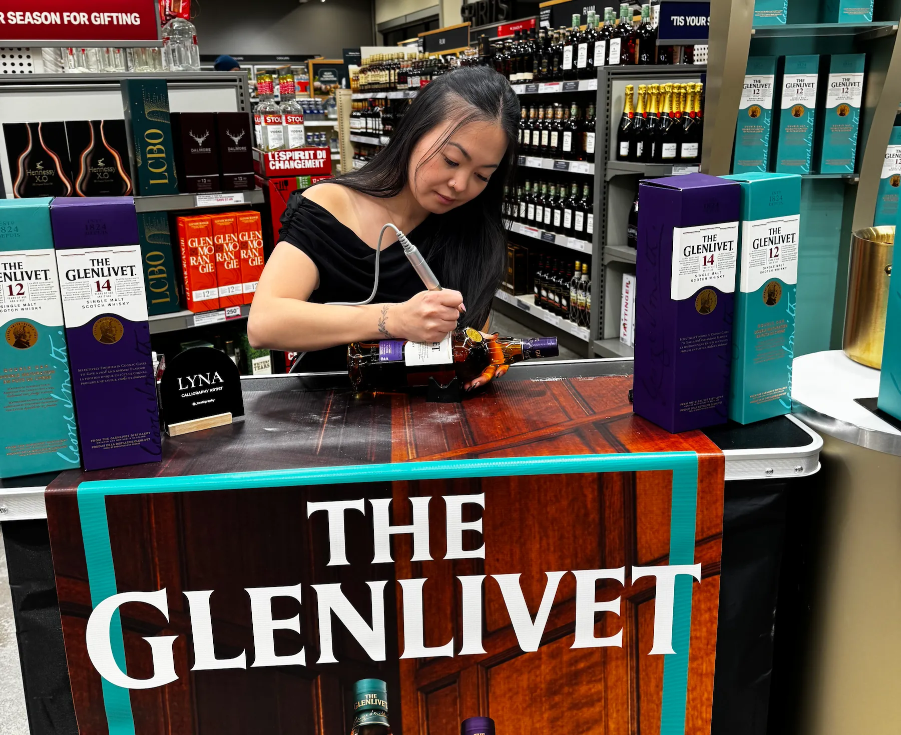 Lyna engraving a bottle at an in-store personalization event.